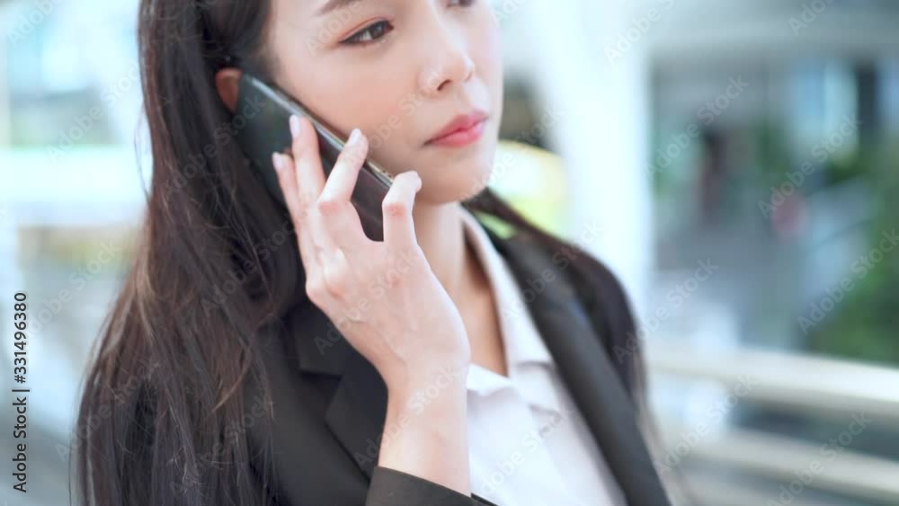 CLose-up Young Asian female calling cell phone while working in the city center CLose-up Young Asian female calling cell phone while working in the city center