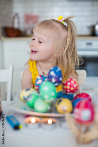 Girl draws easter eggs in the kitchen