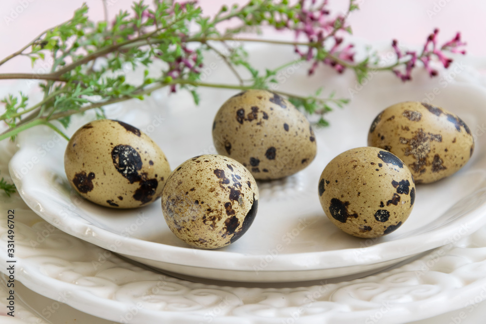 Obraz premium Quail eggs and wild flowers on white vintage plate