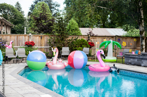 An inviting backyard pool full of hawaiin themed toys.