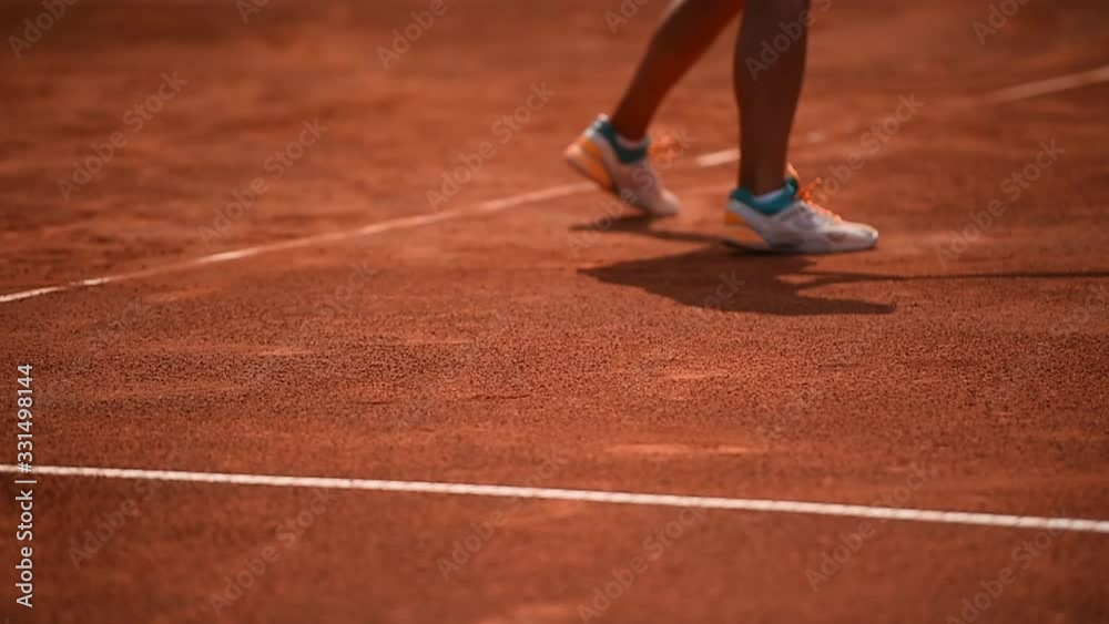 Tennis player and his shadow are seen on a clay court during a competition Tennis player and his shadow are seen on a clay court during a competition