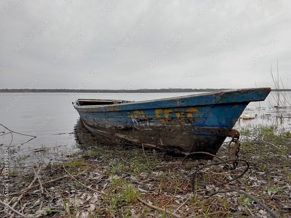 A lonely old boat on a gloomy spring day on the river Bank