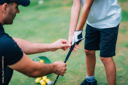 Obraz na plátne Golf Instructor adjusting young boy’s grip