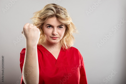 Portrait of female nurse wearing red scrub showing fist