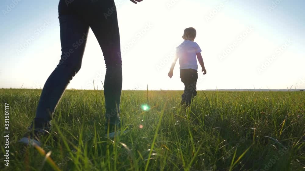 Young loving mom plays with her son outdoors. The child is happy and smiling. Happy family running around on the green grass, enjoying, having fun. The concept is a healthy lifestyle. Young loving mom plays with her son outdoors. The child is happy and smiling. Happy family running around on the green grass, enjoying, having fun. The concept is a healthy lifestyle.