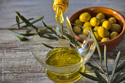 Fototapeta Naklejka Na Ścianę i Meble -  Extra virgin olive oil in a glass bottle, and a enameled clay pot with olives and an olive branch