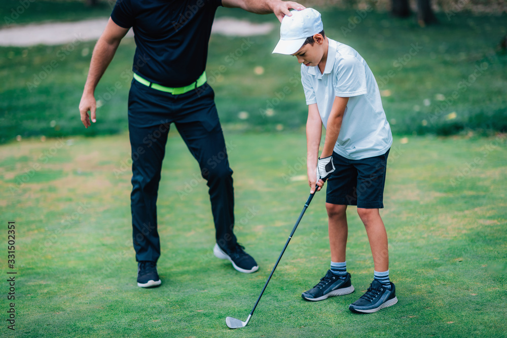 Obraz premium Golf – Personal Training. Golf Instructor Teaching Young Boy How to Play Golf.