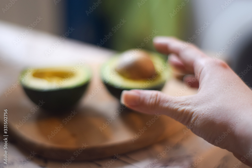 A hand reaches for an avocado A hand reaches for an avocado