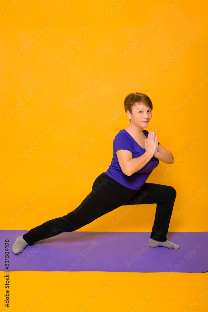 Woman at the age of doing yoga standing on a yellow background. Woman at the age of doing yoga standing on a yellow background.
