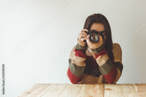 girl at a wooden table uses her analog camera