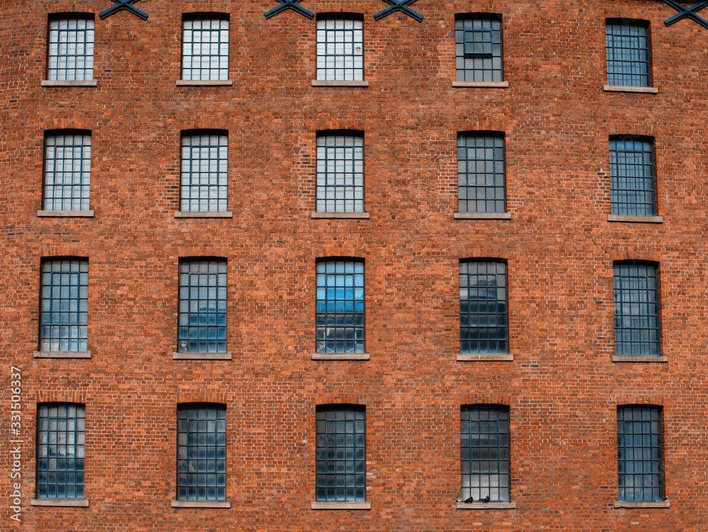 Facade / front  of an old factory building made of red brick with a lot of vintage windows