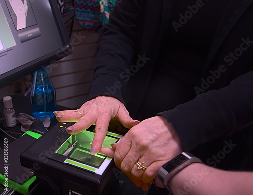 A young woman gets her finger prints scanned live as a requirement to getting a job as a travel occupational therapist. photo