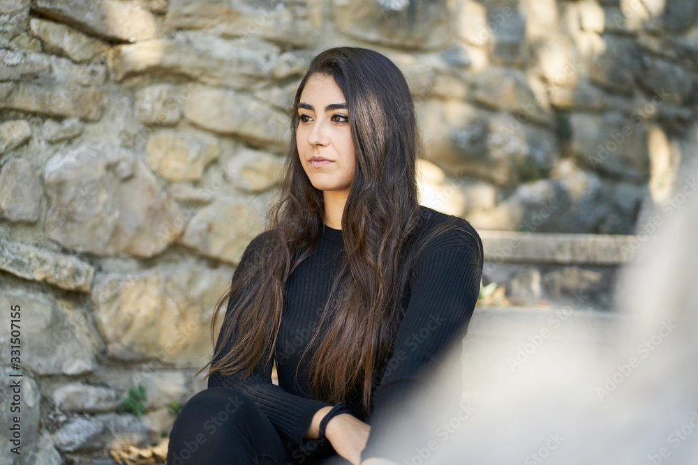 Portrait of a young woman sitting on an urban stone staircase