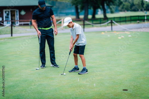 Learning Golf. Boy practicing putting with instructor © Microgen