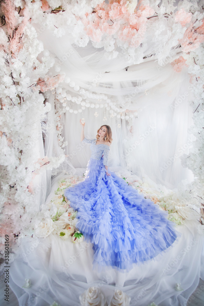 beautiful girl in a blue dress on a bed with flowers beautiful girl in a blue dress on a bed with flowers