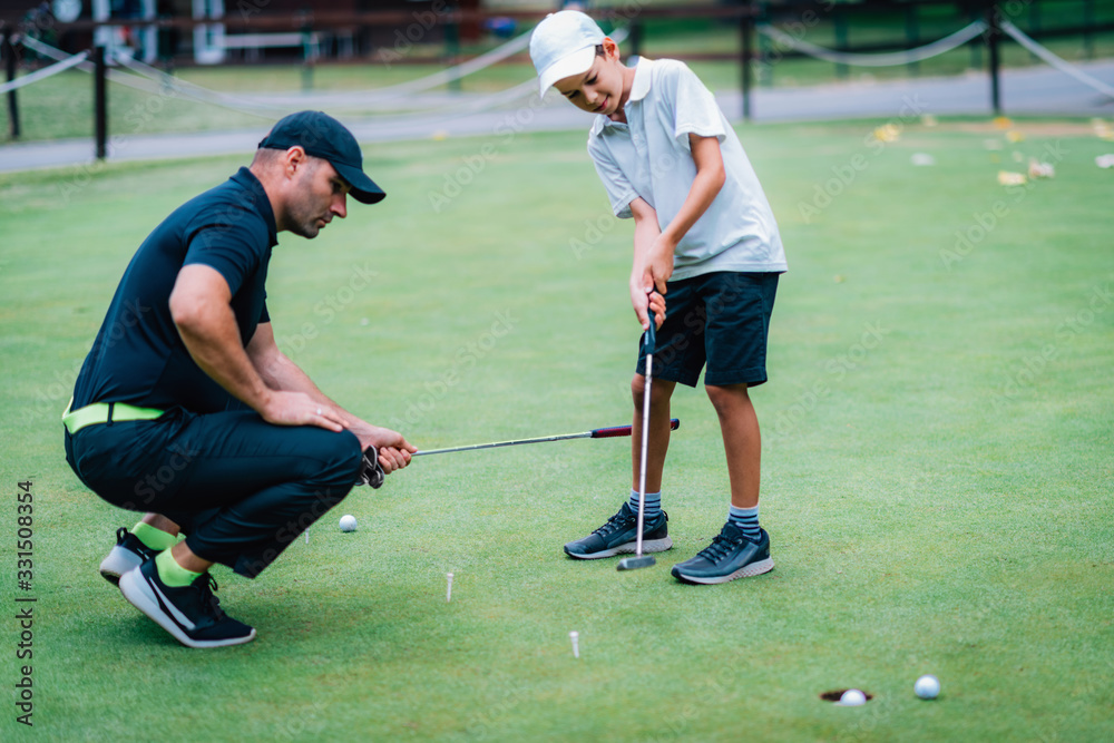 Obraz premium Learning Golf. Boy practicing putting with instructor