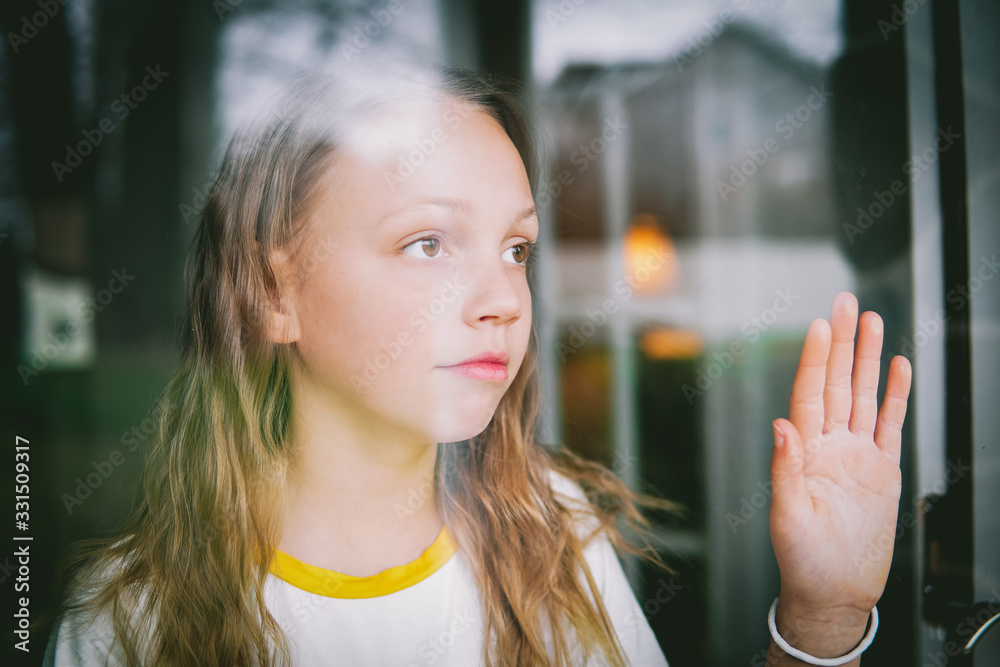 Tween girl bored at home staying inside looking out window quarantine social distancing Tween girl bored at home staying inside looking out window quarantine social distancing