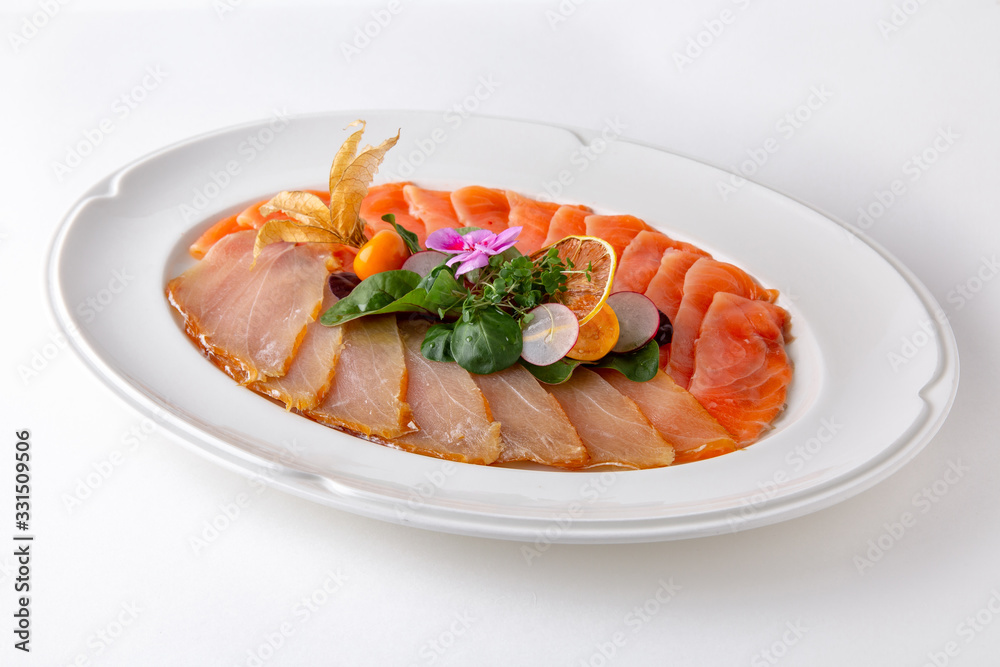 Plate with appetizer of fish and seafood. Sliced salted fish fillet. Smoked salmon, tuna, perch. Banquet festive dishes. Gourmet restaurant menu. White background. Plate with appetizer of fish and seafood. Sliced salted fish fillet. Smoked salmon, tuna, perch. Banquet festive dishes. Gourmet restaurant menu. White background.