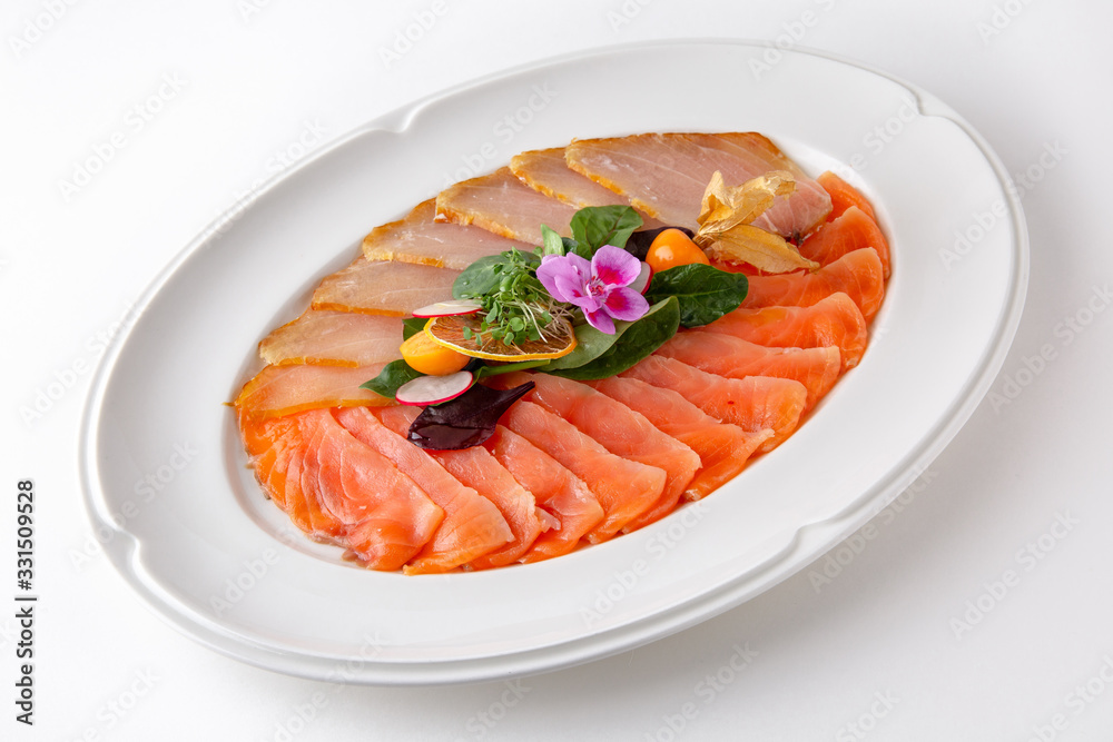 Plate with appetizer of fish and seafood. Sliced salted fish fillet. Smoked salmon, tuna, perch. Banquet festive dishes. Gourmet restaurant menu. White background. Plate with appetizer of fish and seafood. Sliced salted fish fillet. Smoked salmon, tuna, perch. Banquet festive dishes. Gourmet restaurant menu. White background.