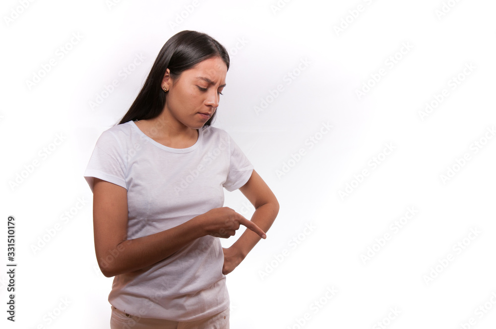 young woman in white clothing on light background looking down and pointing finger down young woman in white clothing on light background looking down and pointing finger down