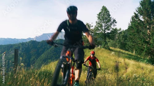 Two men biking riding downhill on a mountain bike trough the forest trails slow motion