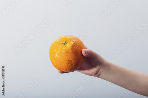 Hand holding isolated orange in white background. Horizontal view.