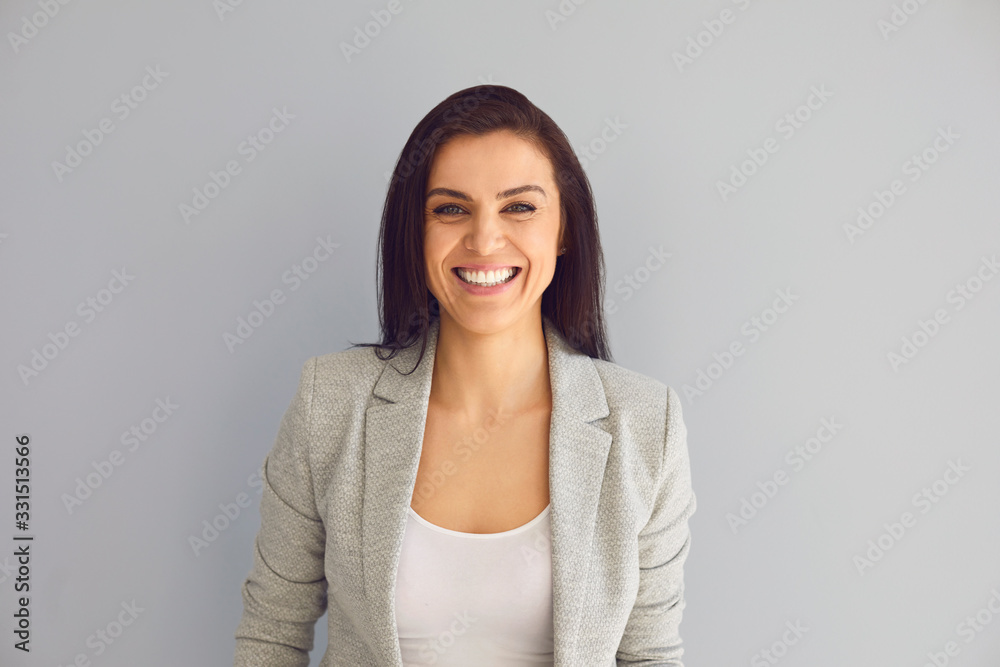 Young woman smiling laughs joyful happy positive on a gray background. Young woman smiling laughs joyful happy positive on a gray background.