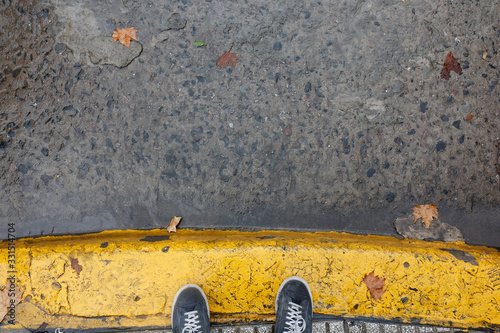 Feet on yellow painted sidewalk curb during a rainig day in Buenos Aires photo