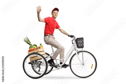 Young man delivering groceries with a tricycle and waving at the camera