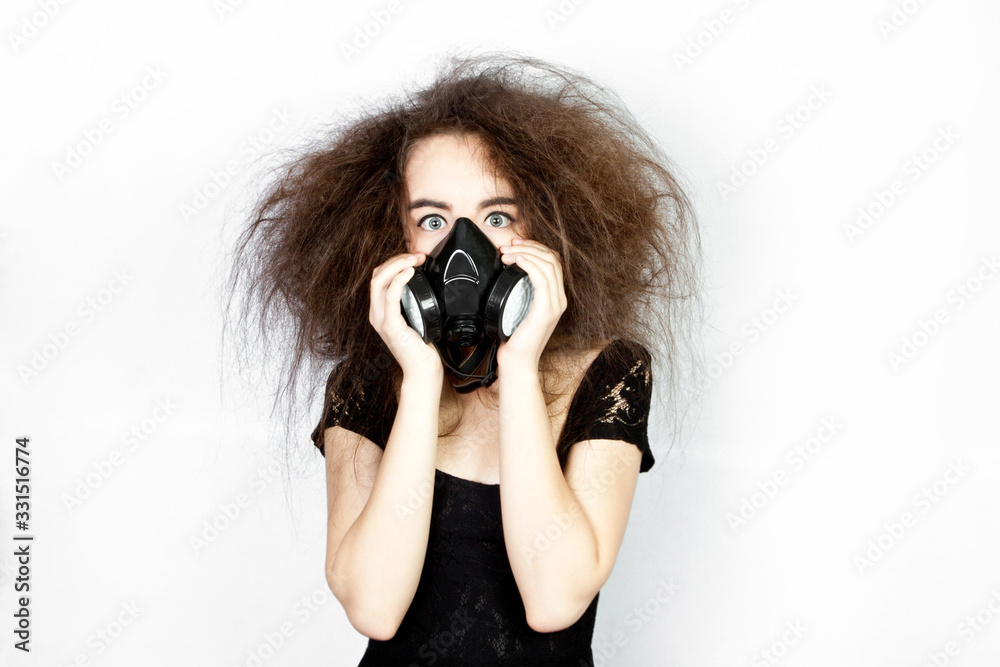 Scared teenager girl in a respirator, with shaggy hair. Respiratory protection. Coronavirus (COVID-19) and healthcare concept. Scared teenager girl in a respirator, with shaggy hair. Respiratory protection. Coronavirus (COVID-19) and healthcare concept.