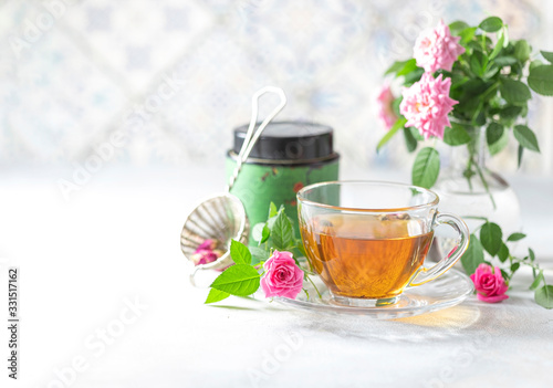 Pink tea buds, a glass cup and vintage strainer. photo