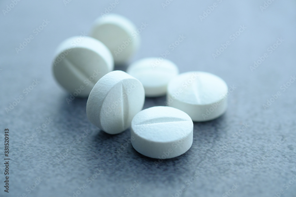 White pills spilling on white background, close up . White pills spilling on white background, close up .