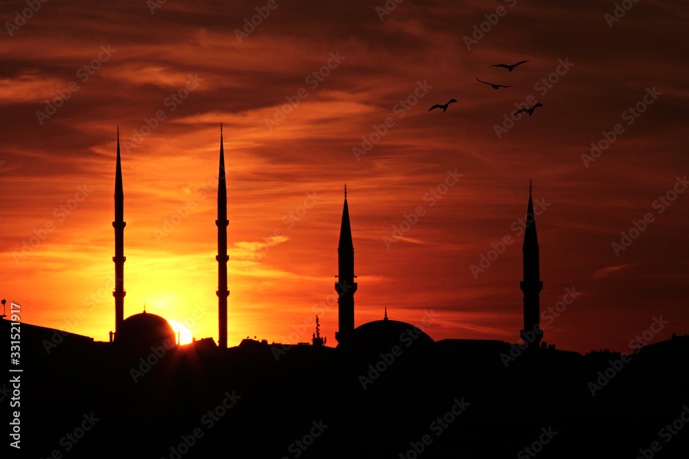 Sunset is down on minarets.Ramadan concept is with silhouette mosques on orange sky.