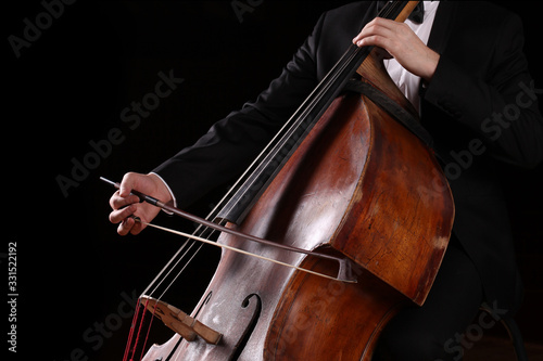Hands of a musician with a bow playing the double bass photo
