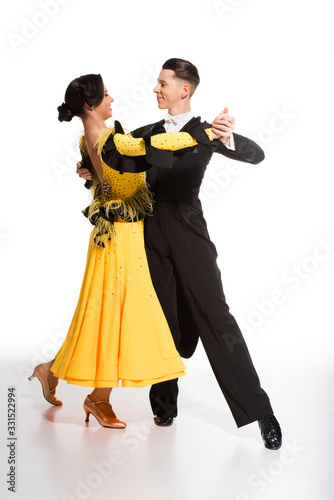 elegant young couple of ballroom dancers dancing on white