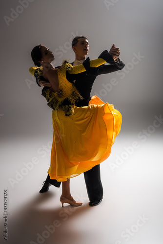 elegant young couple of ballroom dancers dancing in dark