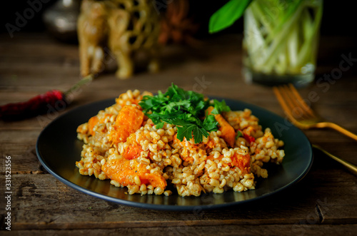 Bulgur with pumpkin on a wooden table. Vegetarian recipes from Indian cuisine.