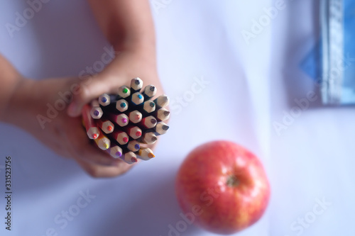 top view of child hand holding color pencils on table 