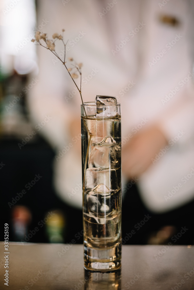 Gin and tonic cocktail in a highball glass decorated with a bunch of dried flowers. Light background. Smooth image with shallow depth of field. Gin and tonic cocktail in a highball glass decorated with a bunch of dried flowers. Light background. Smooth image with shallow depth of field.