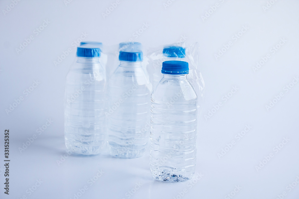 Close-up shot of plastic bottles of water in transparent wrap on white surface Close-up shot of plastic bottles of water in transparent wrap on white surface