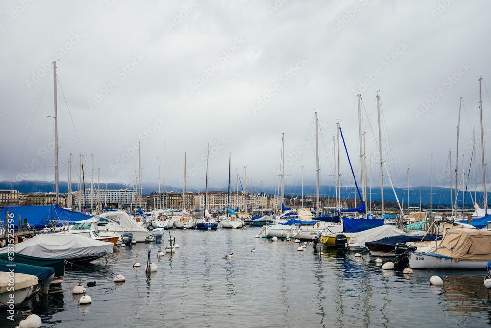 Yachts at the water port in European town, travel, tourism and vacation concept. Photography with white boats and the city lake on cloudy sky background