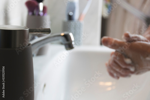 Person washing his hands with soap and water on sink to prevent diseases.