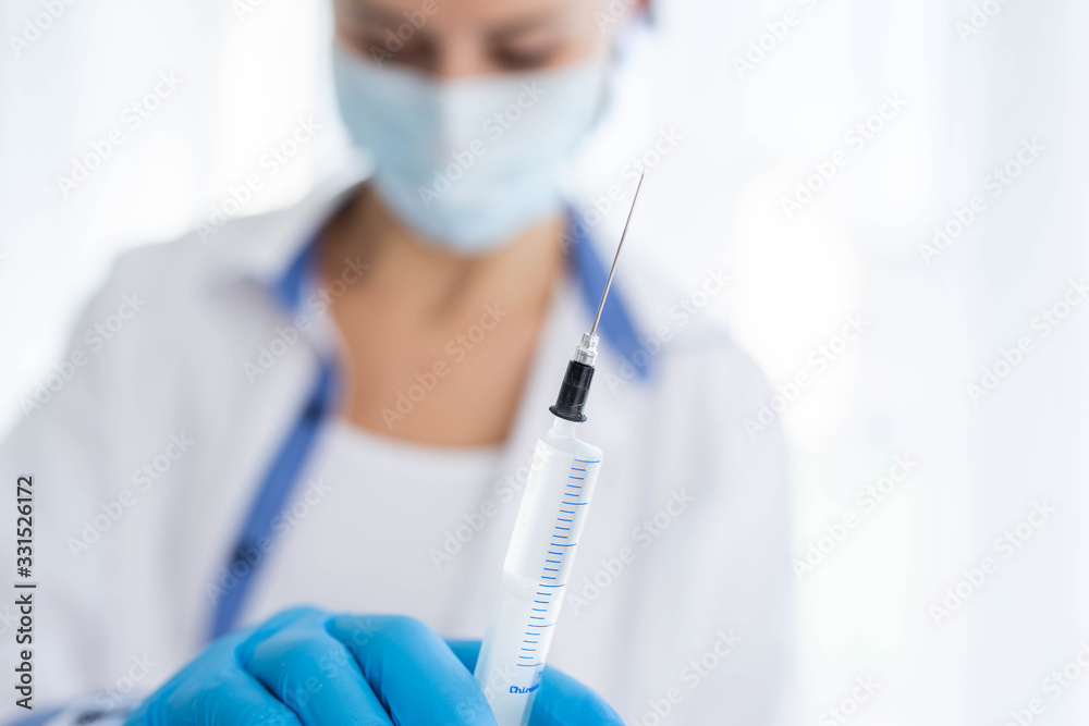 Female doctor or nurse in medical mask holding syringe with injection Female doctor or nurse in medical mask holding syringe with injection
