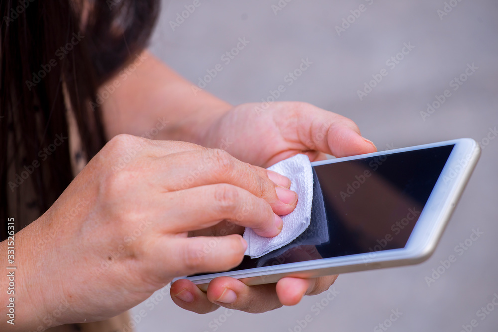 young asian woman cleaning mobile phone screen with soft paper napkin. Coronavirus, Covit-19 prevention and disinfection.