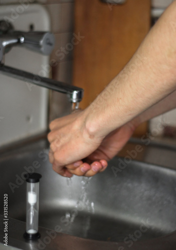 man washing his hands in kitchen sink  sand clock