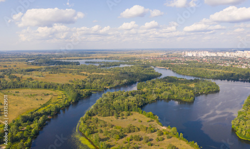 sunny summer day over green islands on a river in a northern city - Aerial Fligh