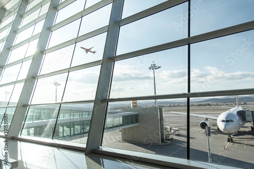 An empty terminal, aircrafts are waiting and preparing for their next flight and one of them taken off photo