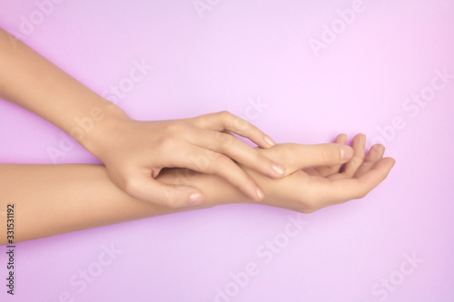 Closeup womens hands on a purple background. Concept of skin care gift certificate. Treatment of sensitive skin. Gentle hand hair removal.
