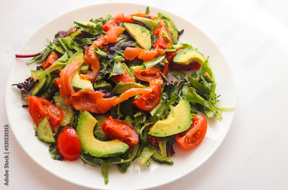 Fresh salad with avocado, salmon and cherry tomatoes on a white plate. Food concept, healthy and organic food Fresh salad with avocado, salmon and cherry tomatoes on a white plate. Food concept, healthy and organic food