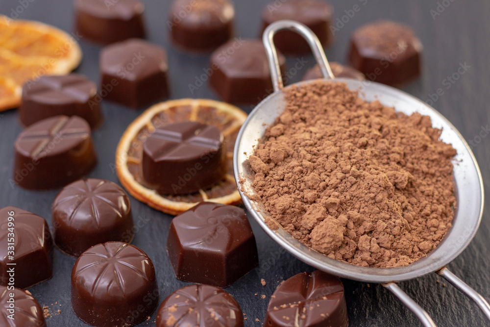 chocolate candies on a black background, cocoa powder. dark photo, mood. chocolate candies on a black background, cocoa powder. dark photo, mood.